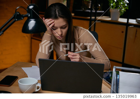 Woman analyzing data while suffering from decision fatigue. Woman analyzing data while suffering from decision fatigue. 135019963