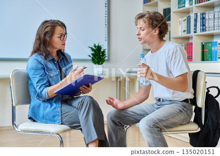 Teenage student guy with school counselor, coach in meeting room 135020151