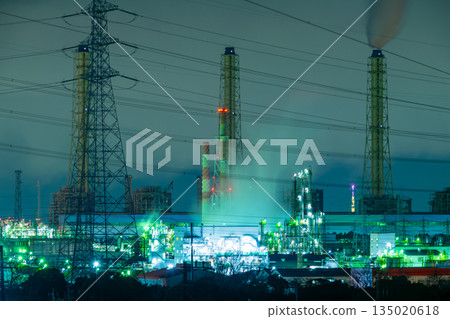 Night view of a huge plant shining at night and a power transmission tower 135020618