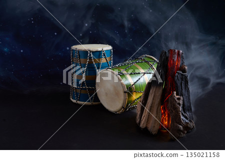 Hand drums with bonfire glowing under starry night sky Hand drums with bonfire glowing under starry night sky 135021158