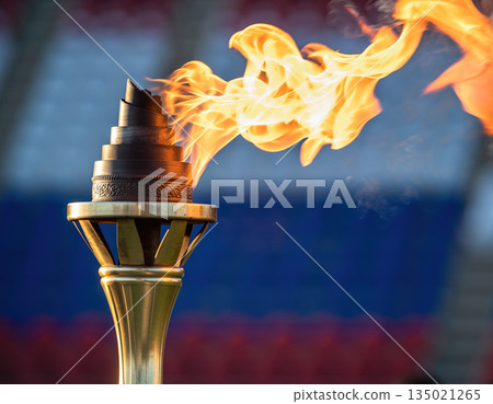 Torch flame burns brightly during a sports event in a stadium with an audience in the background in Russia 135021265