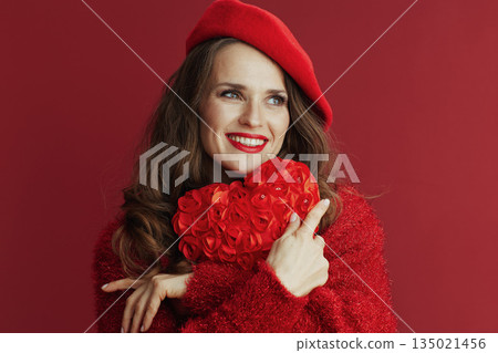 relaxed trendy woman in sweater and beret hugging heart 135021456