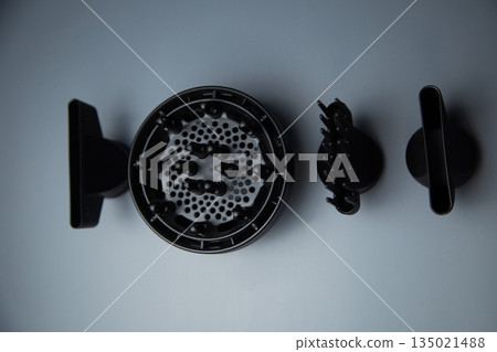 Hairdryer attachments for creating different hairstyles lie on a gray background in the center. The concept of hairstyles, hairstyles with a hairdryer. High quality photo Hairdryer attachments for creating different hairstyles lie on a gray background in the center. The concept of hairstyles, hairstyles with a hairdryer. High quality photo 135021488