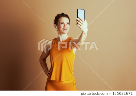 Active Woman Taking Selfie in Mustard Athletic Wear 135021671