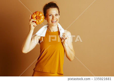 Autumn Harvest: Fitness Woman with Raised Pumpkin Autumn Harvest: Fitness Woman with Raised Pumpkin 135021681