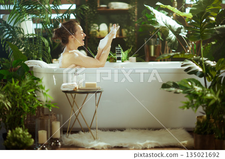 Cheerful Woman Immersed in a Foamy Green Bath 135021692
