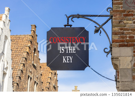 Consistency is the key symbol. Concept words Consistency is the key on black beautiful road sign. Beautiful blue sky and buildings background. Business consistency is the key concept. Copy space. 135021814