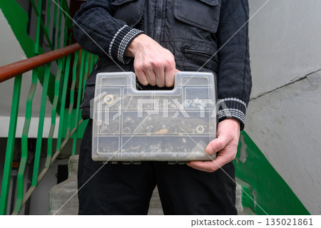 master holds a transparent plastic organizer for hardware in front of him master holds a transparent plastic organizer for hardware in front of him 135021861