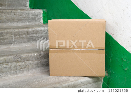 closed brown cardboard box on concrete steps in a house entrance hallway 135021866
