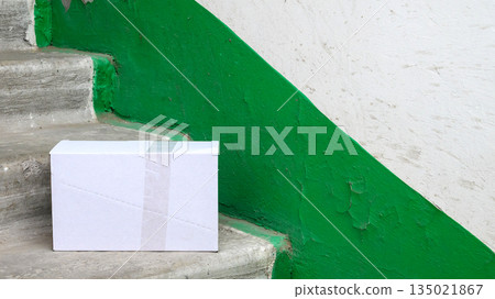 white shipping box located on gray steps inside a staircase area white shipping box located on gray steps inside a staircase area 135021867