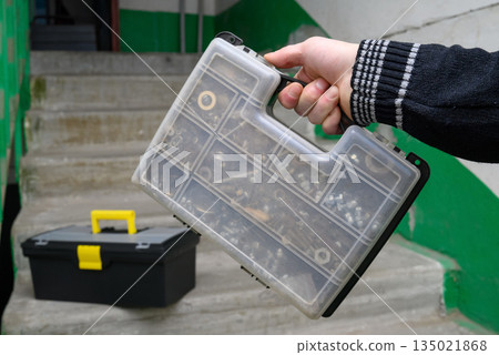 transparent plastic case for storing small fasteners in a master hand in a hallway transparent plastic case for storing small fasteners in a master hand in a hallway 135021868