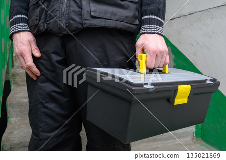 worker carrying a black professional toolbox in a residential building entrance worker carrying a black professional toolbox in a residential building entrance 135021869