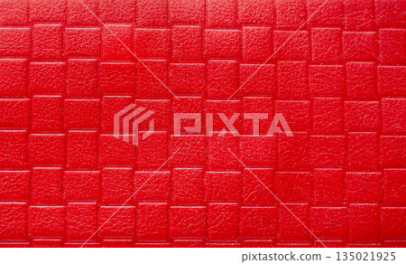 Red embossed leather texture. Close-up of luxurious red leather texture with bold rectangular embossing and matte finish. 135021925