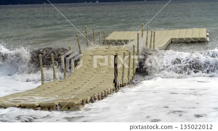 Floating plastic dock on a wavy sea with crashing waves, capturing the raw power of nature and turbulent sea conditions. 135022012