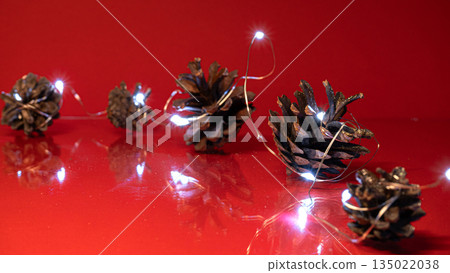 Christmas Pine Cones and Lights on Red Background Christmas Pine Cones and Lights on Red Background 135022038