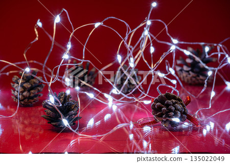Christmas Pine Cones and Lights on Red Background Christmas Pine Cones and Lights on Red Background 135022049