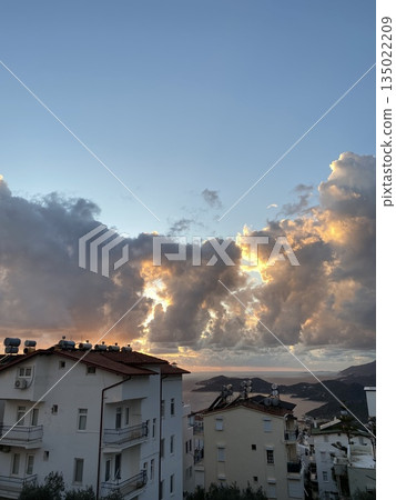 Dramatic sunset sky with sunlit clouds over urban apartment buildings, suitable as background Dramatic sunset sky with sunlit clouds over urban apartment buildings, suitable as background 135022209