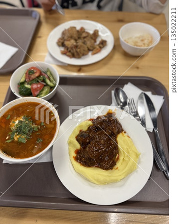 A hearty meal with mashed potatoes, stew, borscht, salad, showing a comforting lunch setting A hearty meal with mashed potatoes, stew, borscht, salad, showing a comforting lunch setting 135022211