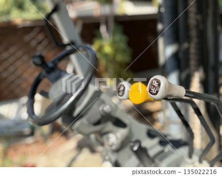 Tractor controls with levers and steering wheel in farm machinery close-up background Tractor controls with levers and steering wheel in farm machinery close-up background 135022216