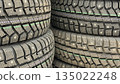 Stacks of studded winter tires arranged closely together, showcasing detailed tread patterns 135022248