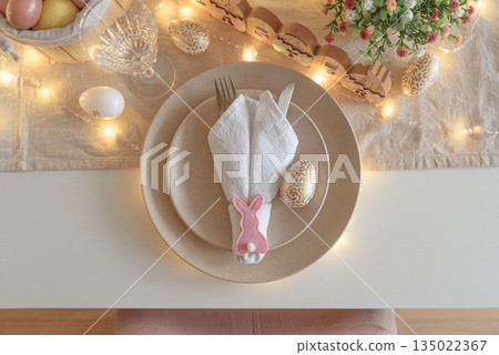 Festive Easter table setting with Easter bunny made from napkin decorated lights. Easter celebration concept. Top view 135022367