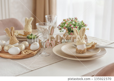 Festive Easter table setting with Easter bunny made from egg and knitted ears. Easter celebration concept Festive Easter table setting with Easter bunny made from egg and knitted ears. Easter celebration concept 135022370