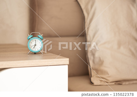 Retro turquoise alarm clock on a bedside table. Retro turquoise alarm clock on a bedside table. 135022378