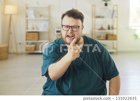 Angry man shouting and pointing in bright home interior, showing conflict Angry man shouting and pointing in bright home interior, showing conflict 135022635