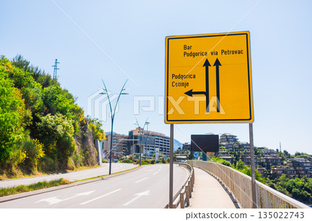 Road sign on coastal highway indicating directions across Montenegro. Transportation infrastructure, navigation clarity, travel planning, and modern roadside environment near Budva Road sign on coastal highway indicating directions across Montenegro. Transportation infrastructure, navigation clarity, travel planning, and modern roadside environment near Budva 135022743