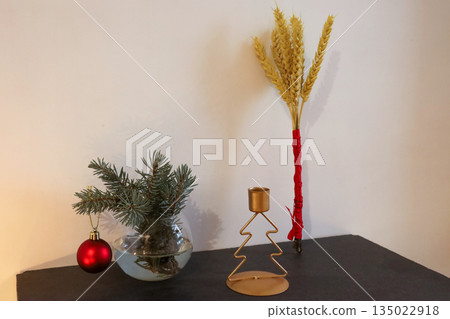 Christmas arrangement with pine branches red ornaments tree candle holder and wheat didukh tied with red ribbon. Christmas arrangement with pine branches red ornaments tree candle holder and wheat didukh tied with red ribbon. 135022918