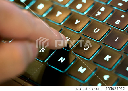 Typing on a laptop keyboard at night Typing on a laptop keyboard at night 135023012