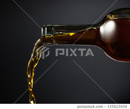 White wine of a rich amber color pours out of the bottle. White wine of a rich amber color pours out of the bottle. 135023039
