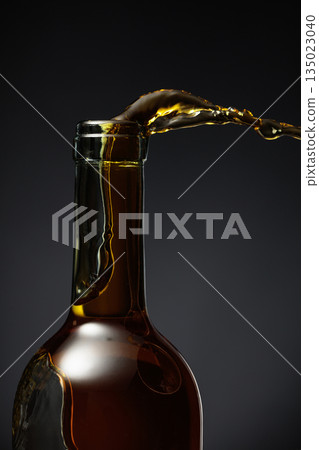 White wine of a rich amber color pours out of the bottle. White wine of a rich amber color pours out of the bottle. 135023040