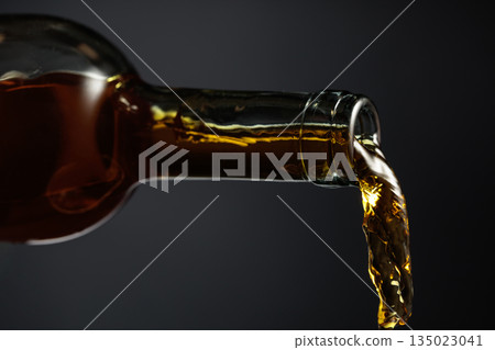 White wine of a rich amber color pours out of the bottle. 135023041