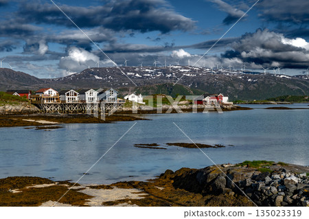 Coastal Landscape With Calm Fjord, Snowy Mountains With Wind Turbines And Cottages On Sommaroy Island In Norway Coastal Landscape With Calm Fjord, Snowy Mountains With Wind Turbines And Cottages On Sommaroy Island In Norway 135023319