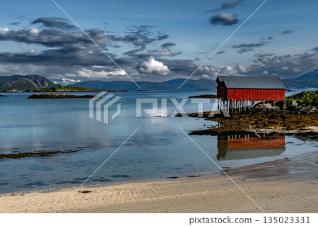 Sandy Beach And Red Hut Cottage In Front Of Mountains On Sommaroy Island At Calm Fjord In Norway 135023331