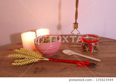 Kutia nuts candles and didukh tied with red ribbon on a traditional Christmas table. Kutia nuts candles and didukh tied with red ribbon on a traditional Christmas table. 135023444