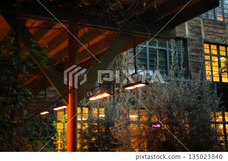 Outdoor cafe with infrared heaters suspended from ceiling to comfort visitors during cold season Outdoor cafe with infrared heaters suspended from ceiling to comfort visitors during cold season 135023840