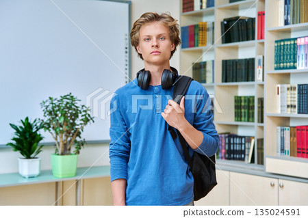 Portrait of serious teenage student with backpack in classroom library Portrait of serious teenage student with backpack in classroom library 135024591
