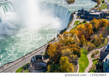 Horseshoe Falls shrouded in mist and the Niagara Falls skyline illuminated by autumn foliage 135024664