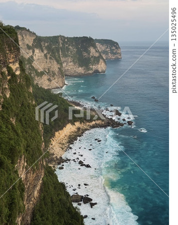Nusa Penida, Indonesia, Pantai Atuh, rocks, ocean, balihigh cliff trail overlooking turquoise coastline, steep escarpment dotted with boulders, waves breaking on distant shoals, vegetated ledges and 135025496