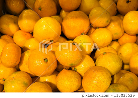 vibrant pile ripe mandarins glowing in warm light, market crate closeup showcasing dewy skin, scattered stems, glossy texture, vivid orange color, harvest abundance and commercial freshness ready for vibrant pile ripe mandarins glowing in warm light, market crate closeup showcasing dewy skin, scattered stems, glossy texture, vivid orange color, harvest abundance and commercial freshness ready for 135025529