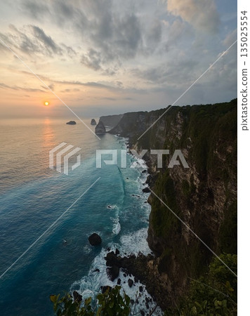 Nusa Penida, Indonesia, rocks, ocean, balisunset light spilling across towering coastal cliffs, golden glow on rock faces, soft cloudscape, silhouette of distant islets, calm sea reflecting warm Nusa Penida, Indonesia, rocks, ocean, balisunset light spilling across towering coastal cliffs, golden glow on rock faces, soft cloudscape, silhouette of distant islets, calm sea reflecting warm 135025554