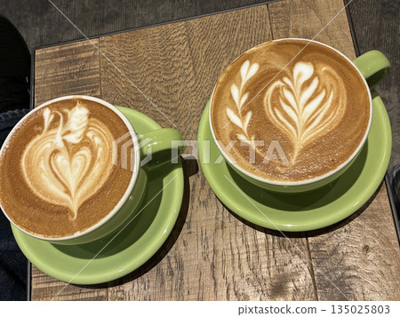 Two cups of cafe lattes with latte art on a wooden table 135025803