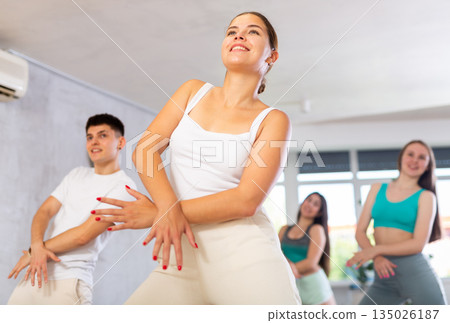 Girl teen perform choreographic exercise and teach energetic house dance with friends Girl teen perform choreographic exercise and teach energetic house dance with friends 135026187