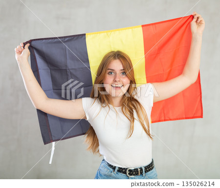 smiling girl in arms raised above head holds canvas of national flag of Belgium. smiling girl in arms raised above head holds canvas of national flag of Belgium. 135026214