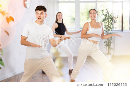 Girls and guys dancing synchronous group choreography in dance hall 135026233