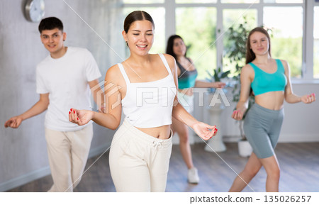Young girl practicing vigorous dance movements in group dance class Young girl practicing vigorous dance movements in group dance class 135026257