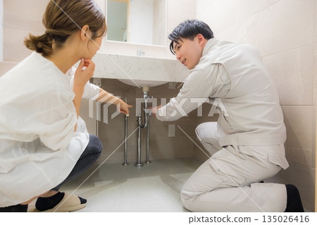 A man wearing work clothes and a woman requesting repairs 135026416