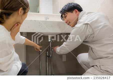A man wearing work clothes and a woman requesting repairs 135026417